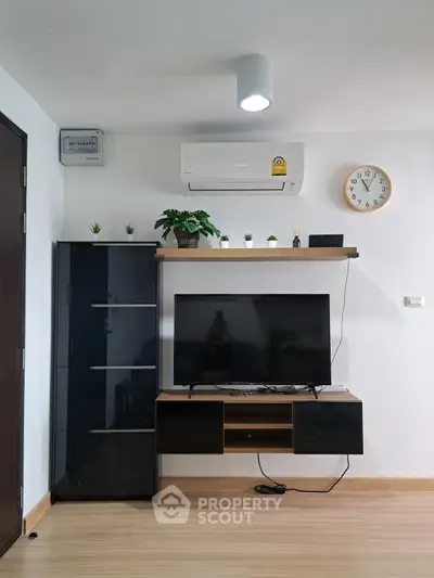 Modern living room with sleek TV stand, air conditioning, and minimalist decor.