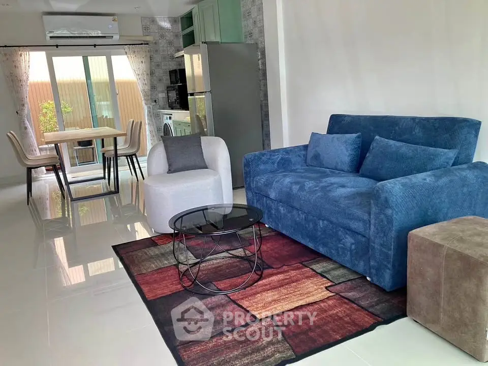 Modern living room with stylish blue sofa and dining area, featuring open layout and natural light.