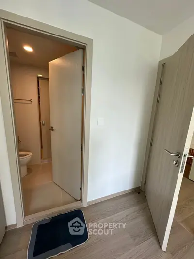 Modern bathroom entrance with wooden doors and sleek flooring