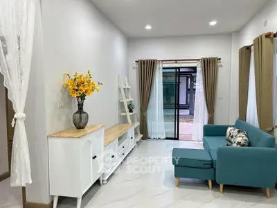 Charming living room with modern decor, featuring a teal sofa, white furniture, and elegant curtains.