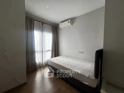 Cozy minimalist bedroom with natural light and air conditioning, perfect for relaxation.