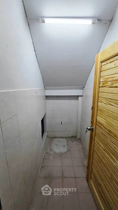 Compact storage room with tiled walls and wooden door, ideal for extra space in your home.