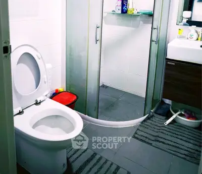 Modern bathroom with shower, toilet, and sink in a compact layout.