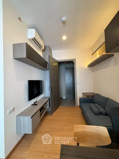 Modern living room with sleek furniture and wall-mounted TV in a cozy apartment.