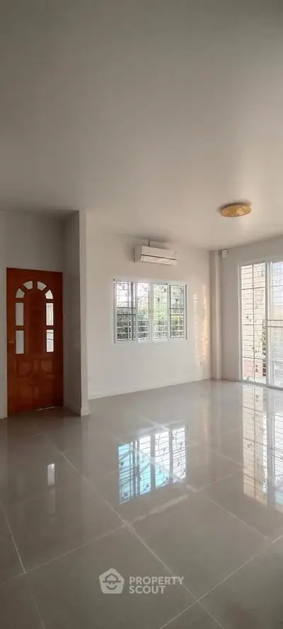 Spacious living room with large windows and glossy tiled floors