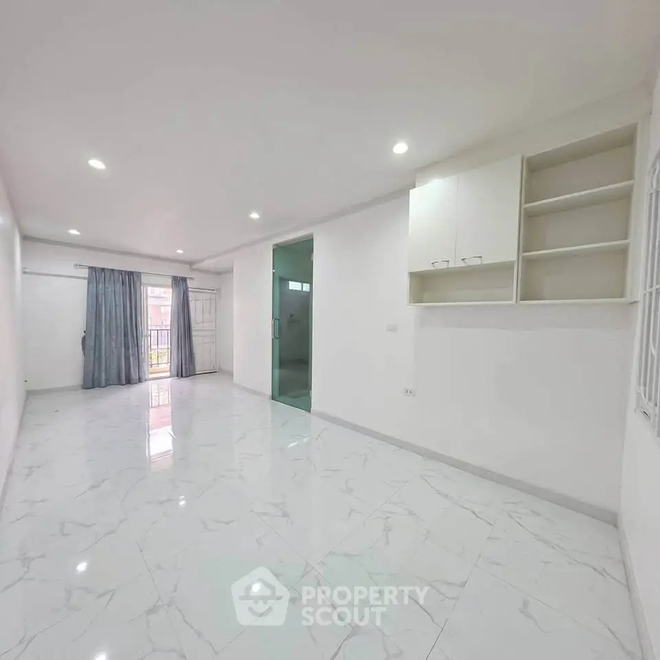 Spacious and bright living room with marble flooring and built-in shelves, perfect for modern living.