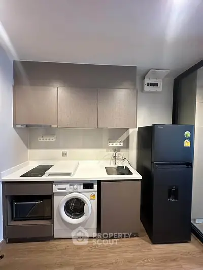 Modern kitchen with sleek appliances including washing machine and fridge, compact yet stylish design.