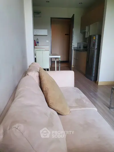 Spacious living area seamlessly connects to a modern kitchen, featuring plush sofa, ample natural light, and sleek appliances for a comfortable urban living experience.