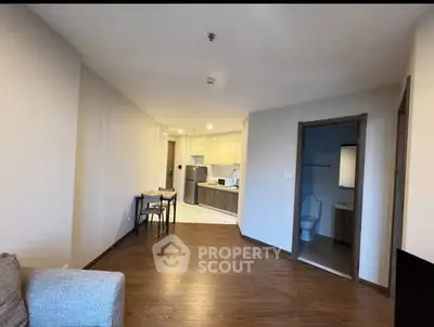 Spacious open-plan living area with modern kitchen and wooden flooring in a cozy apartment.