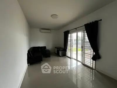 Spacious living room with modern sofa and large glass doors opening to a garden view.
