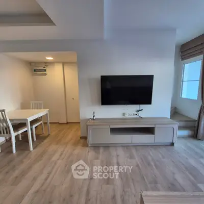 Modern living room with wall-mounted TV and dining area in open layout