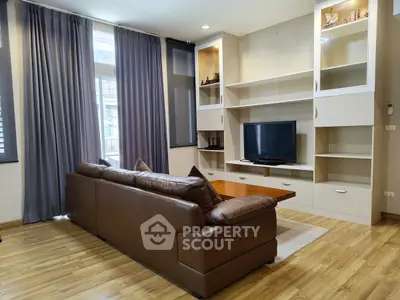 Spacious living room with modern leather sofa and built-in entertainment center.