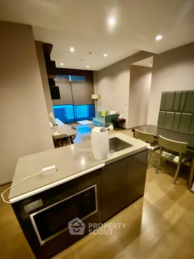 Modern open-layout kitchen with sleek appliances and cozy living area in a stylish apartment.