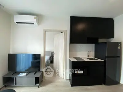 Modern apartment interior with sleek kitchen and cozy living area, featuring air conditioning and flat-screen TV.
