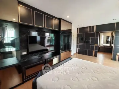 Luxurious modern bedroom with elegant black and gold decor, featuring a large mirror and built-in TV.