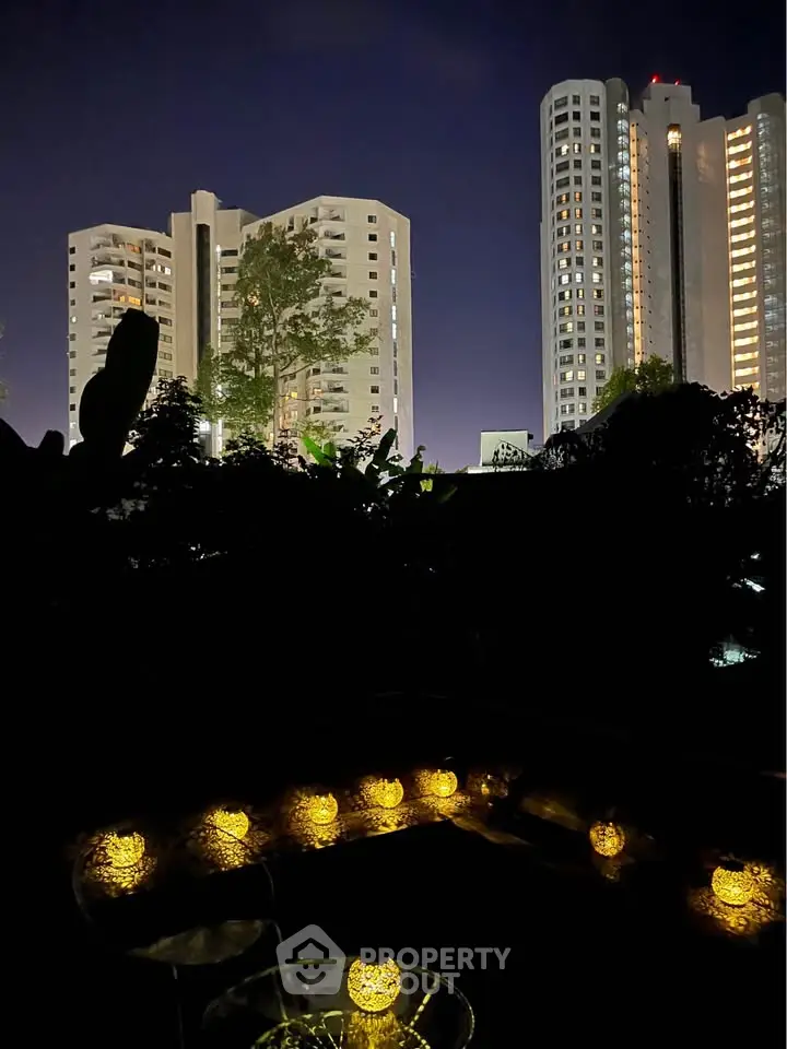 Stunning night view of modern high-rise buildings with illuminated windows and decorative outdoor lighting.