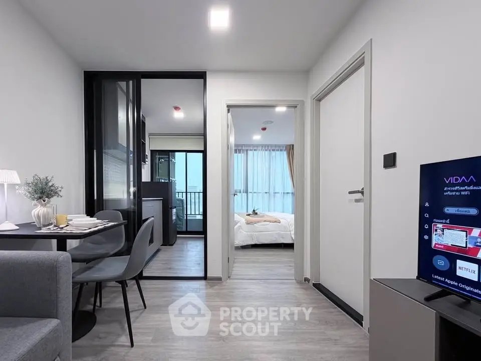 Modern apartment interior with open living area and bedroom, featuring sleek furniture and natural light.