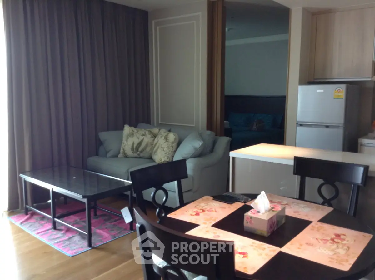 Modern living room with cozy sofa, dining table, and kitchen area in open layout apartment.