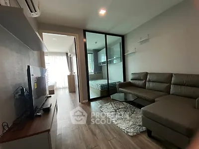 Modern living room with sleek furniture and open layout leading to a cozy bedroom.