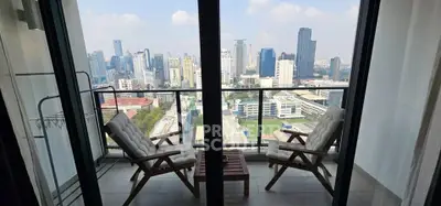 Stunning city view from a high-rise balcony with cozy seating, perfect for relaxation.