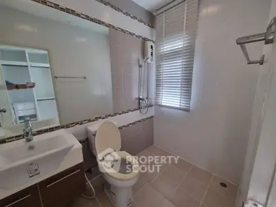 Modern bathroom with sleek fixtures and large mirror, featuring a shower and toilet.