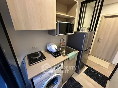 Modern compact kitchen with washing machine and microwave in stylish apartment.