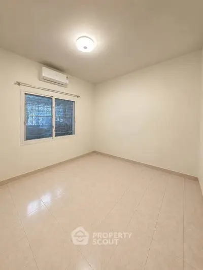 Spacious empty room with tiled floor and air conditioning, perfect for customization.