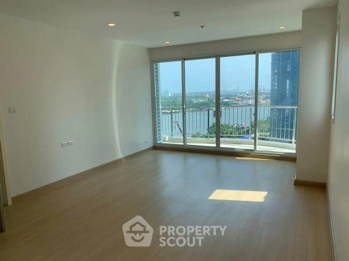 Spacious living room with large windows offering stunning river view in modern apartment.