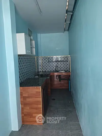 Compact kitchen with modern backsplash and wooden cabinetry in a narrow space.