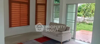 Bright living room with modern sofa and large windows overlooking a lush garden.