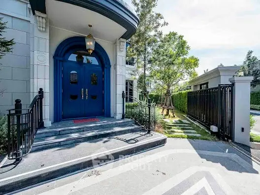 Elegant entrance with blue double doors and lush greenery, perfect for luxury living.