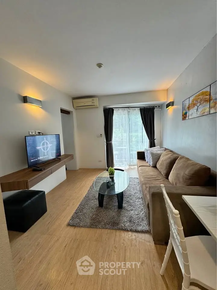 Modern living room with cozy sofa, TV, and natural light from large window.