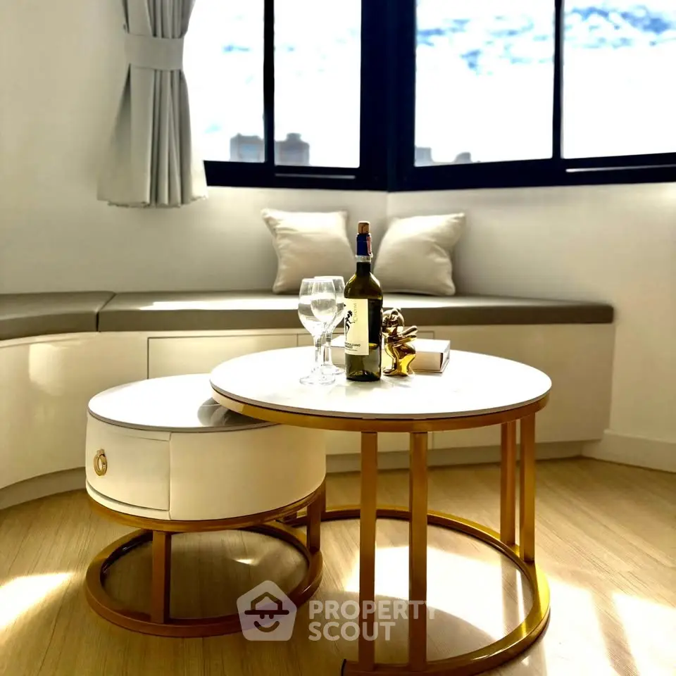 Chic living room with elegant round table, wine setup, and cozy seating by large windows.