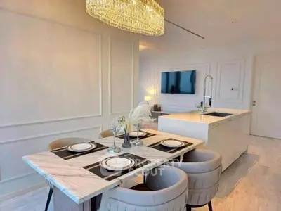 Luxurious open-plan kitchen and dining area with elegant chandelier and modern decor.