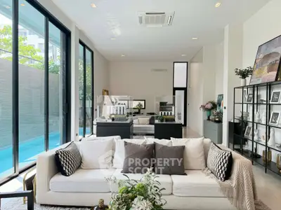 Luxurious living room with pool view, modern decor, and abundant natural light.