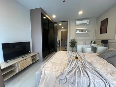 Modern bedroom with stylish decor, TV, and workspace in a cozy apartment.