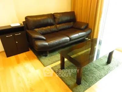 Cozy living room with leather sofa and glass coffee table in modern apartment.