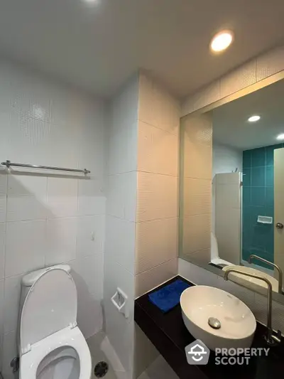 Modern bathroom with sleek white tiles, well-lit vanity area, and a spacious shower, perfect for a refreshing start to the day.