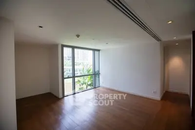 Spacious empty living room with large window and wooden flooring