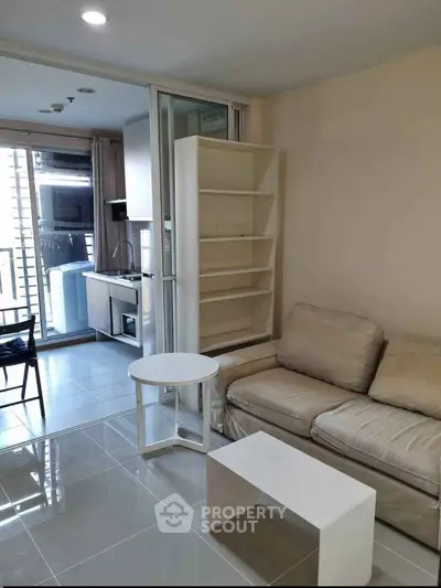 Modern living room with beige sofa, open kitchen, and balcony view in a stylish apartment.