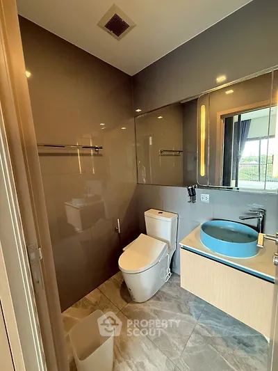 Modern bathroom with sleek design, featuring a stylish blue basin and contemporary fixtures.