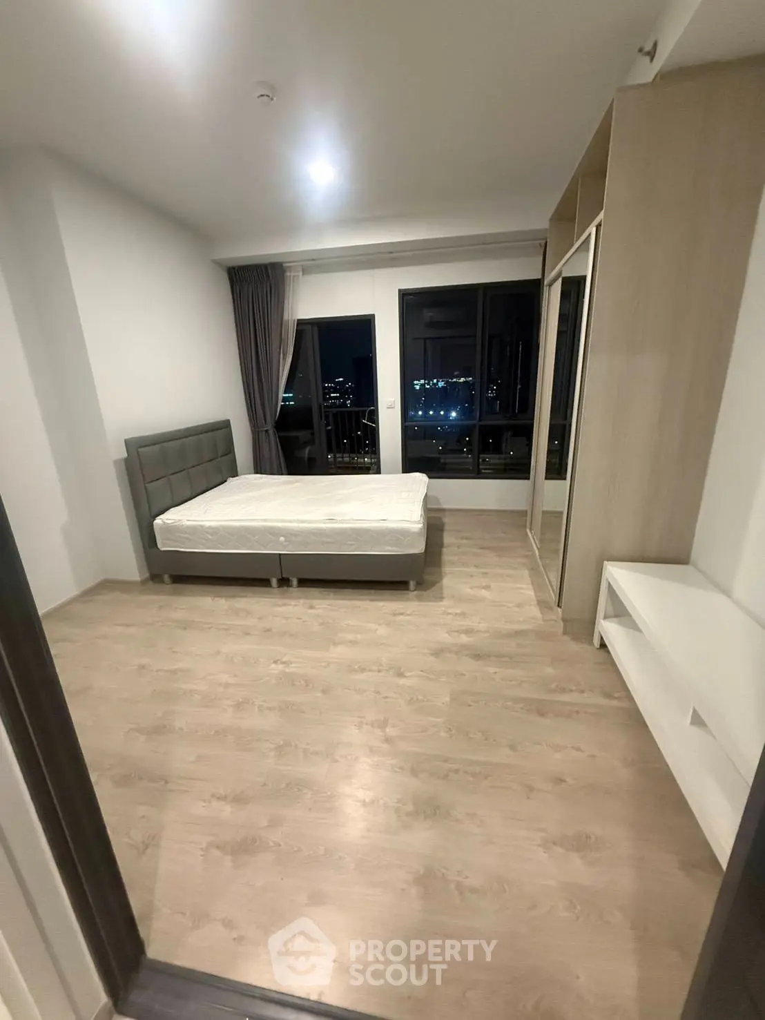Spacious bedroom with city view, featuring modern furnishings and large windows for natural light.