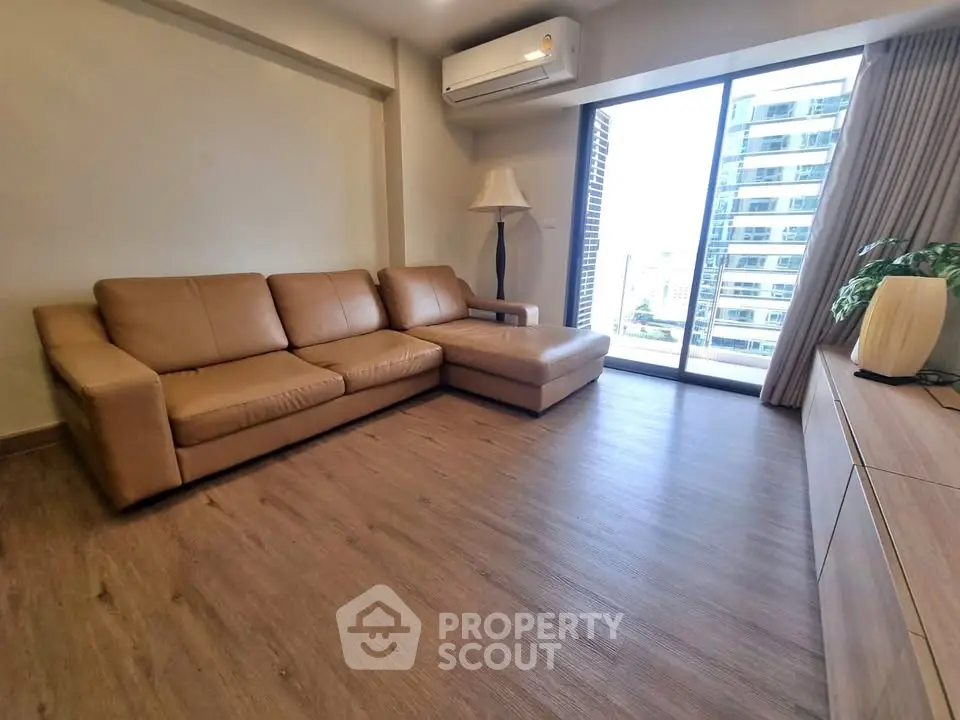 Modern living room with leather sofa and city view from large window.