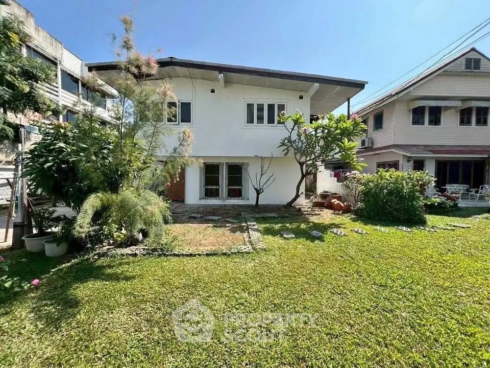 Charming two-story house with lush garden and spacious lawn in a serene neighborhood.