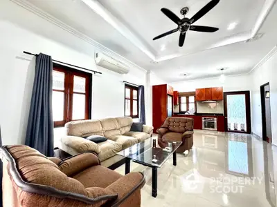 Spacious living room with modern furniture and open kitchen layout in a bright, airy home.