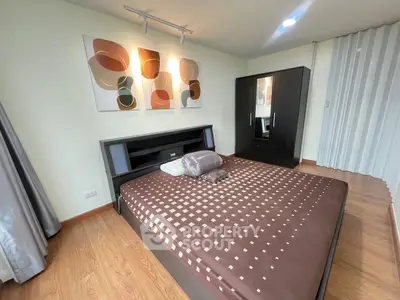 Modern bedroom with stylish decor and wooden flooring, featuring a sleek wardrobe and contemporary artwork.