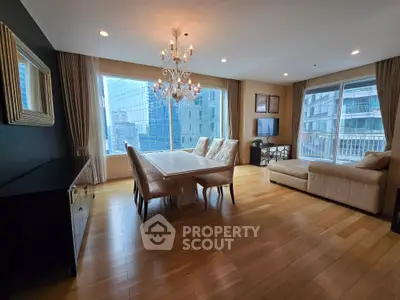 Luxurious living room with elegant chandelier and city view, featuring hardwood floors and plush seating.
