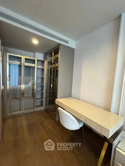 Modern study room with sleek desk and built-in glass cabinets in a luxury apartment.