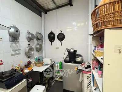 Compact kitchen with washing machine and hanging cookware, ideal for efficient space use.