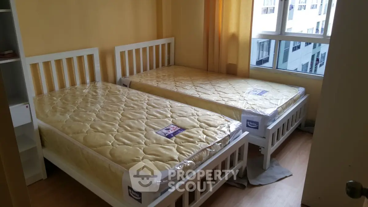 Cozy bedroom with twin beds and large window in modern apartment